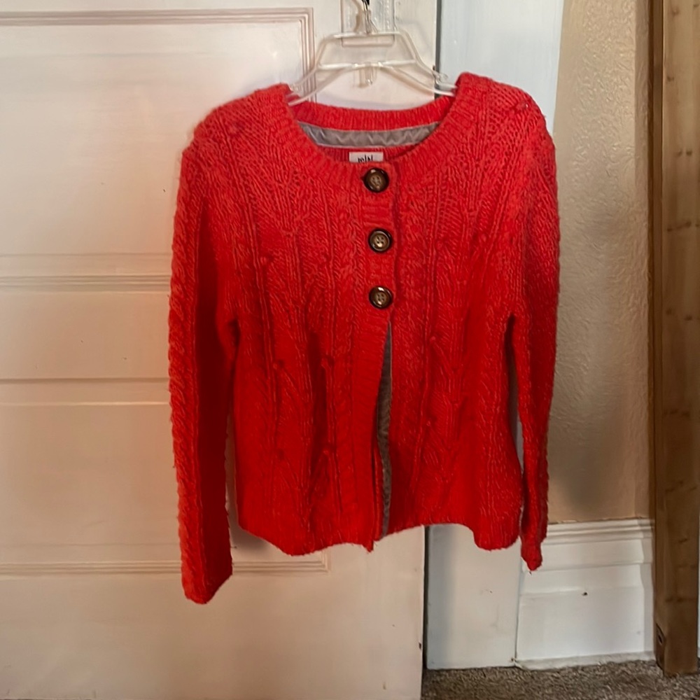 A reddish, orange sweater with 3 buttons